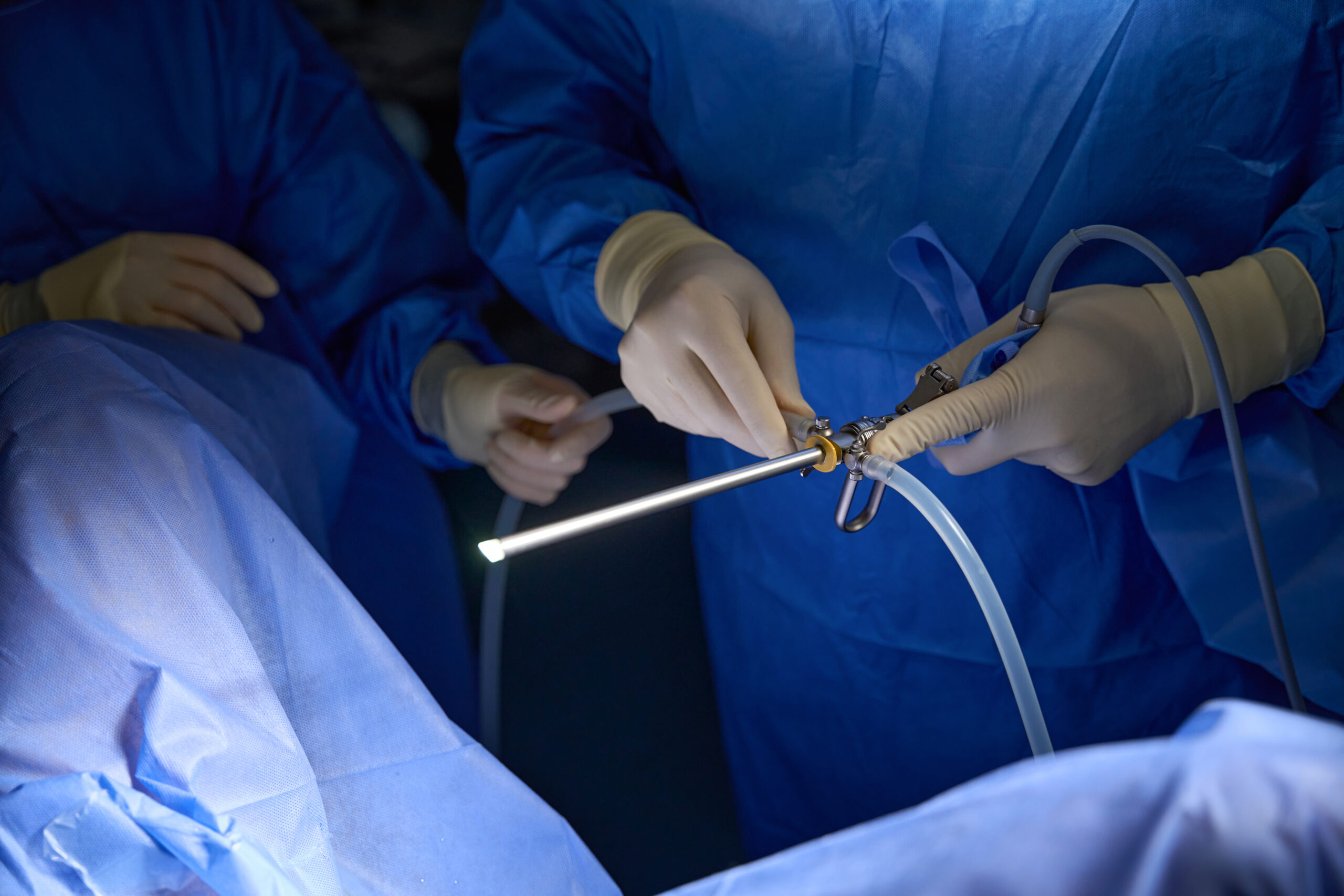 Close up of medical team performing surgery in operating room, using surgical laparoscopy equipment