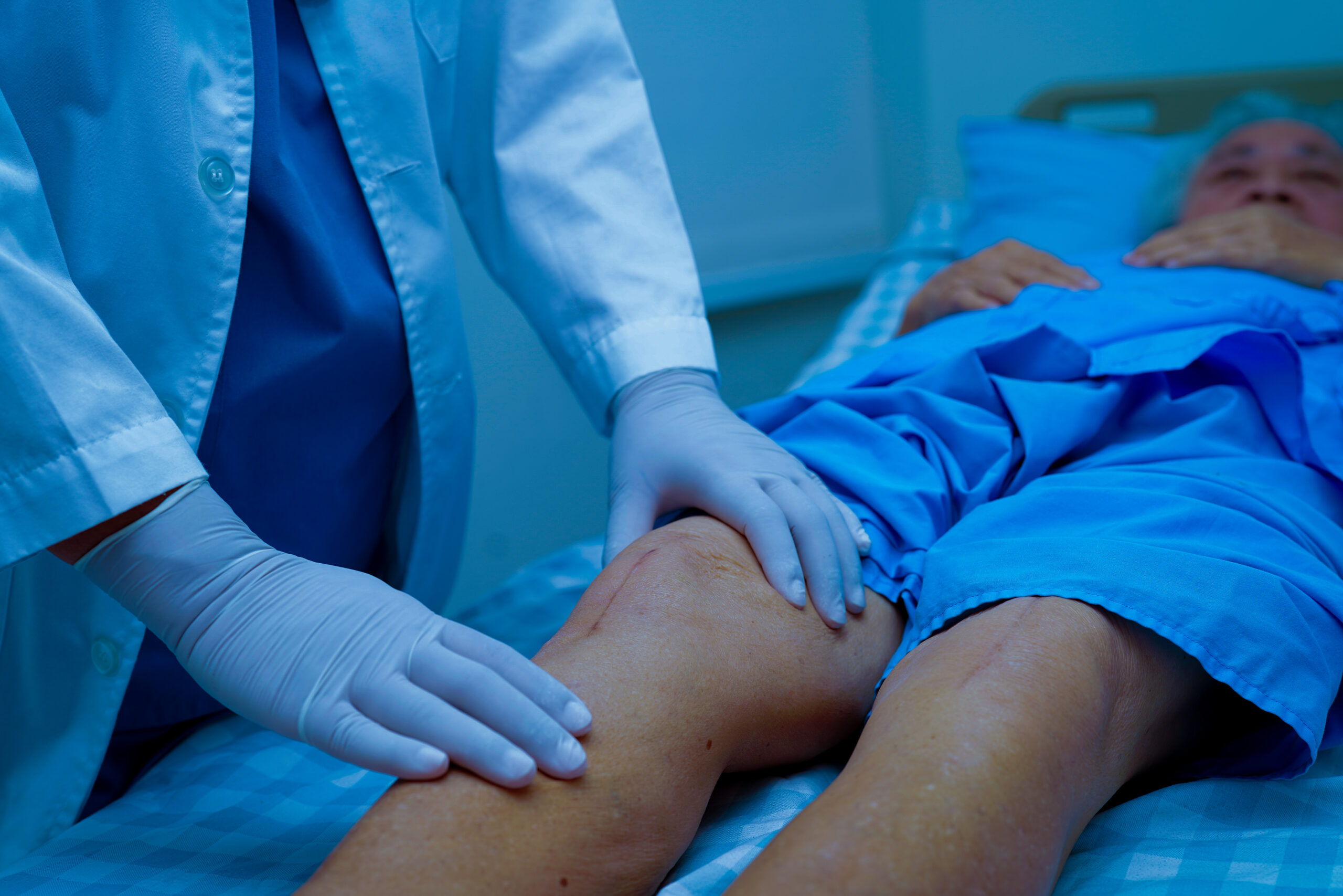 Doctor checking Asian elderly woman patient with scar knee repla